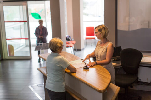 femme blonde à l'accueil de la mairie recevant une femme à la recherche d'informations