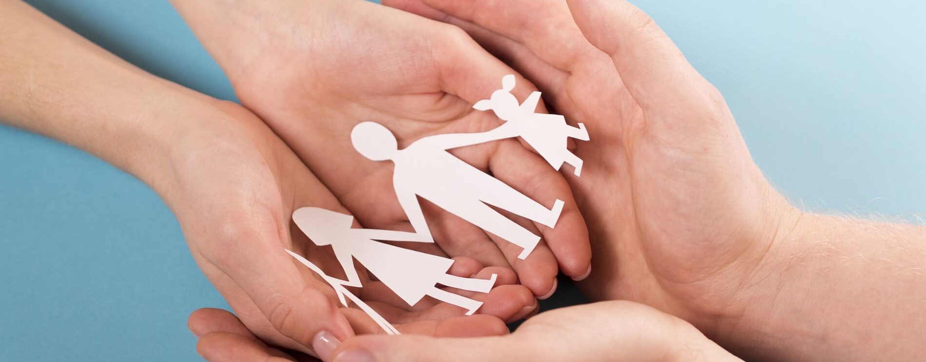 mains tenant dans leur creu une guirlande blanche de papier représentant une famille