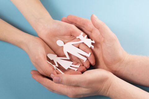 mains tenant dans leur creu une guirlande blanche de papier représentant une famille