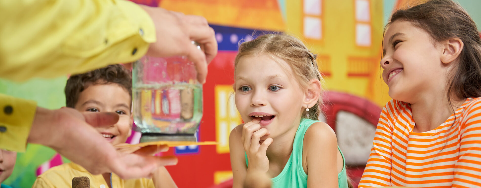 groupes d'enfants qui regardent un adulte faire une expérience avec de l'eau