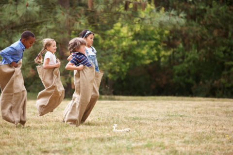 enfants faisant une course en sac sur un terrain d'herbe