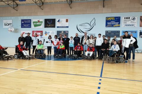 groupe de oersonnes rassemblées dans une salle de sport autour du maire de guipavas. Certaines personnes sont en fauteuil roulant.