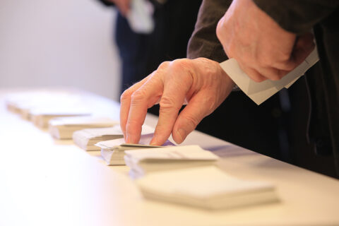 Homme qui choisit un bulletin de vote. Zoom sur ses mains