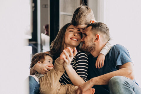Famille composée de 2 parents et de 2 jeunes enfants qui s'amusent ensemble