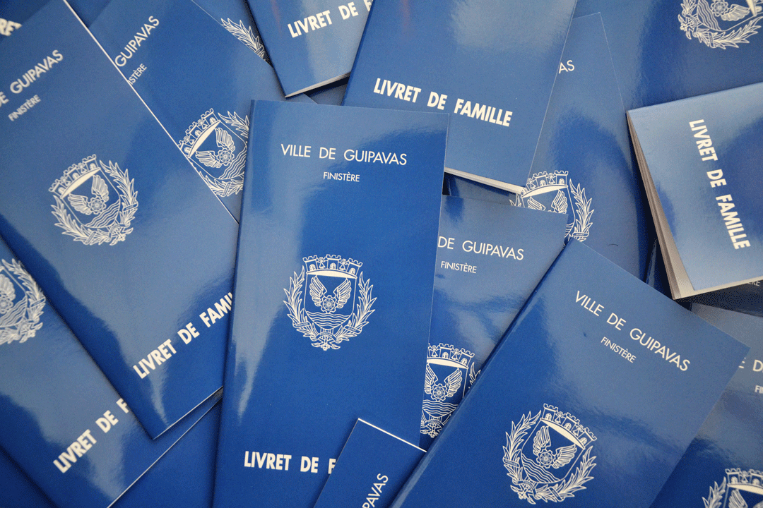 plusieurs livrets de famille étalés sur une table. couverture bleue et mention de la ville de guipavas sur la couverture