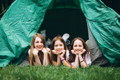 3 enfants dans une tente verte en pleine nature